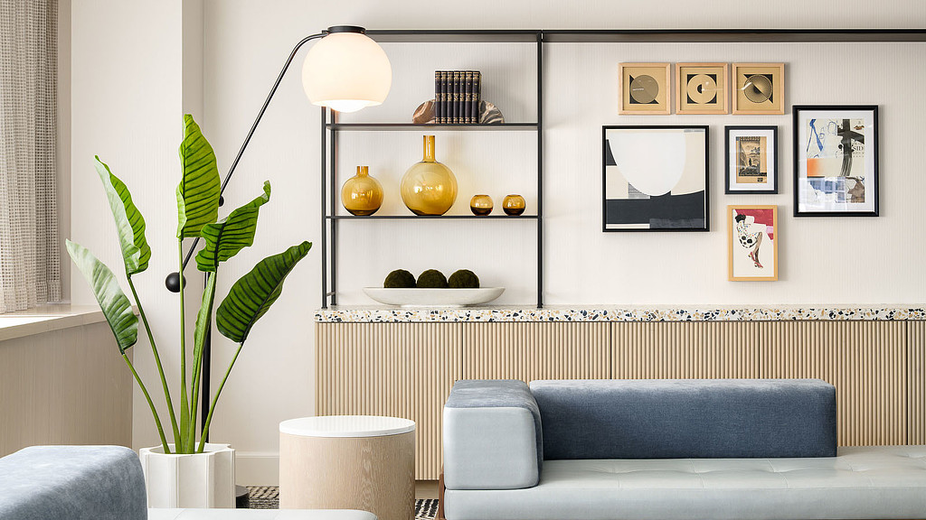 A room with a couch and a table with a plant on it.